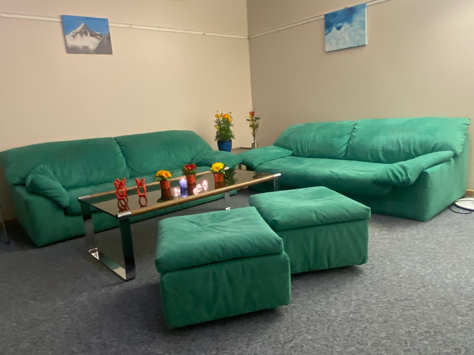 La salle d'accueil du café-deuil, canapés verts et bougies